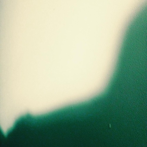 A grainy, abstract photo of a shadow against a plain wall