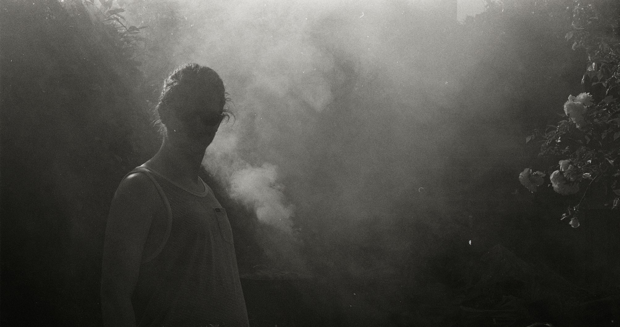 Black and white photo of Patrick Young, Raconteur, deep in BBQ smoke
